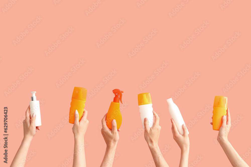 Female hands with bottles of sunscreen cream on color background