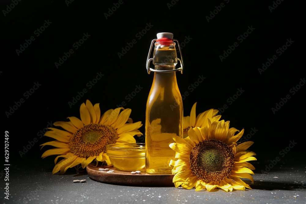 Bottle and glass bowl of sunflower oil with seeds on black background