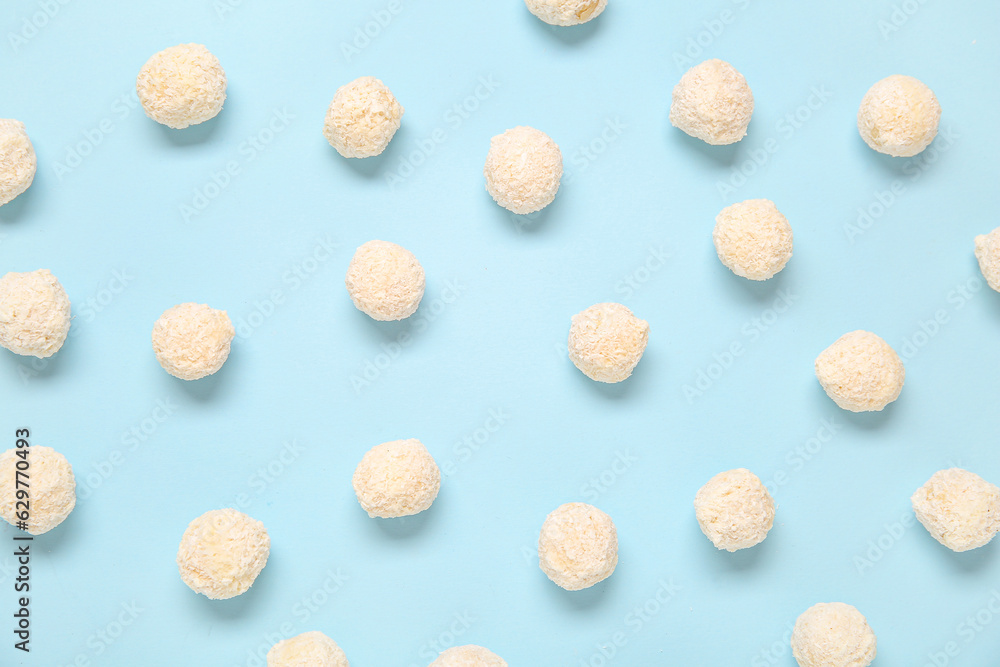 Many white chocolate candies with coconut topping on blue background