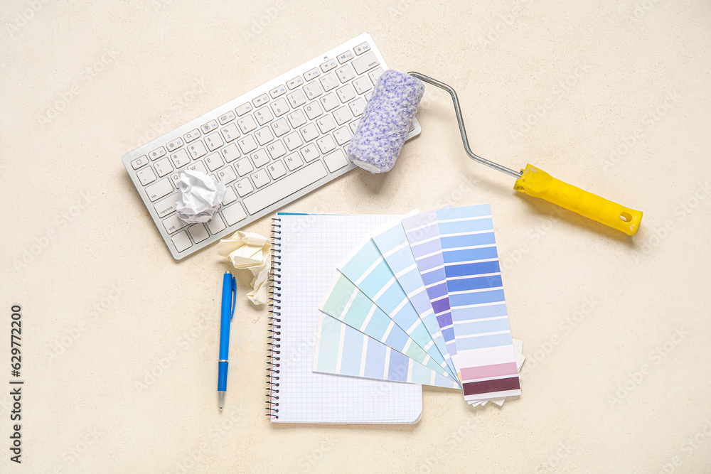 Color palettes, PC keyboard, paint roller and notebook on light background, top view