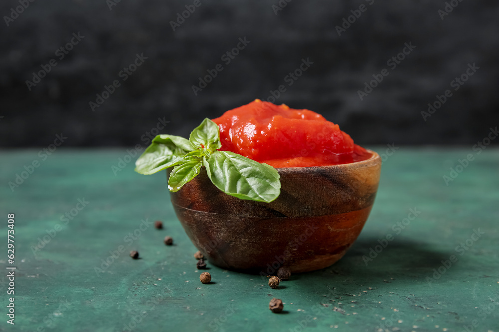 Bowl of canned tomatoes and peppercorns on color background