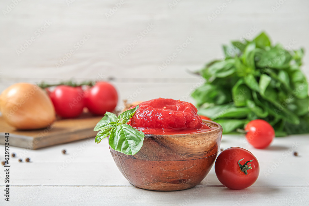 Bowl of canned tomatoes on light wooden table