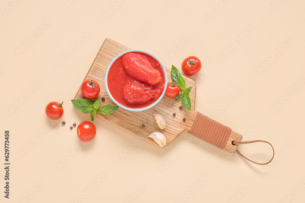 Wooden board with canned, fresh tomatoes and spices on color background