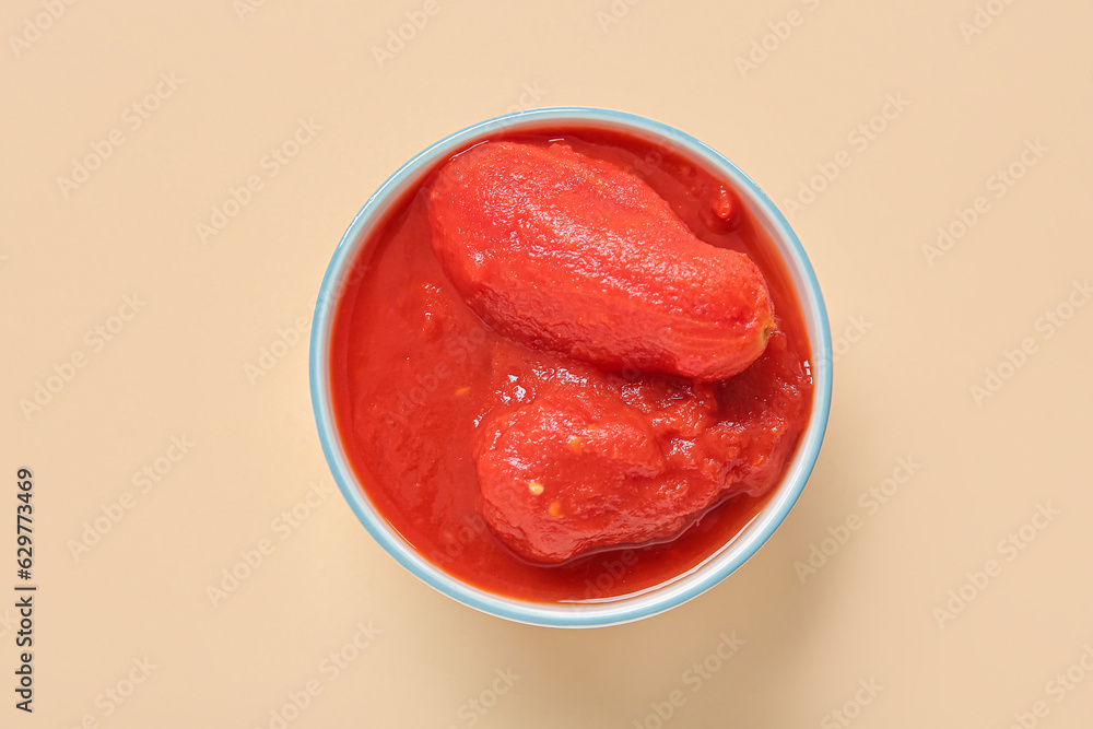 Bowl of tasty canned tomatoes on color background