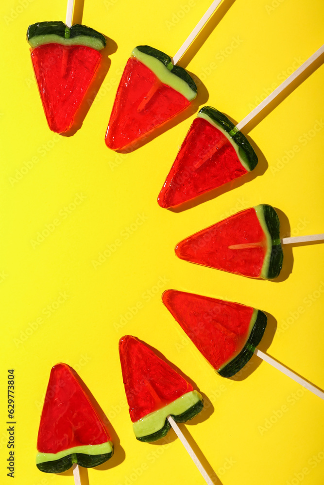 Lollipops in shape of watermelon slice on yellow background