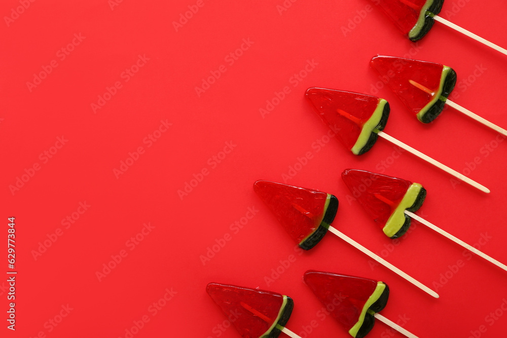 Lollipops in shape of watermelon slice on red background