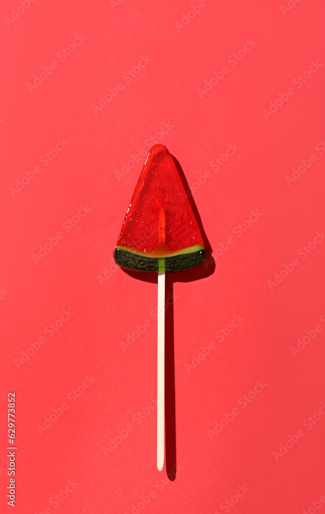 Lollipop in shape of watermelon slice on red background