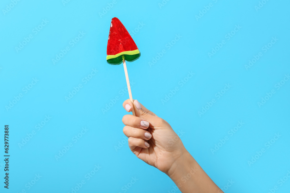 Woman holding lollipop in shape of watermelon slice on blue background