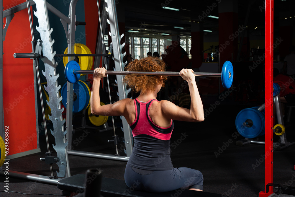 Woman bodybuilder engaged with a barbell in the gym