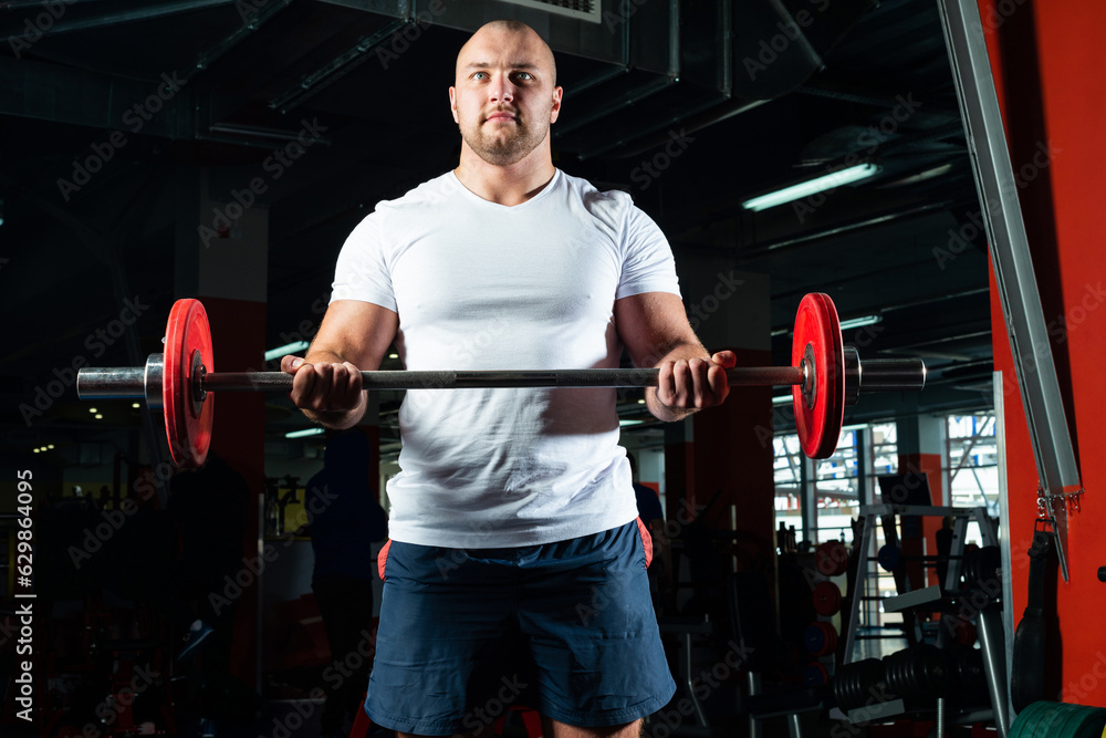 Male athlete lifts the barbell