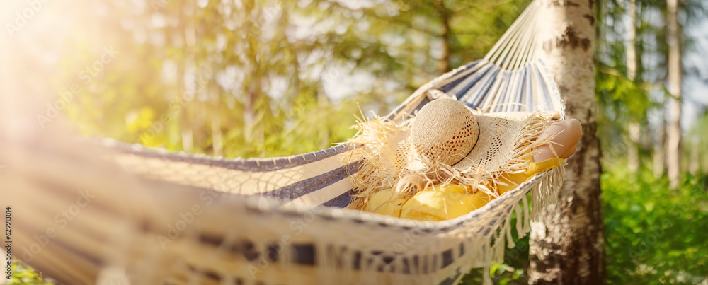 Woman lying in the hammock with hat on her face.