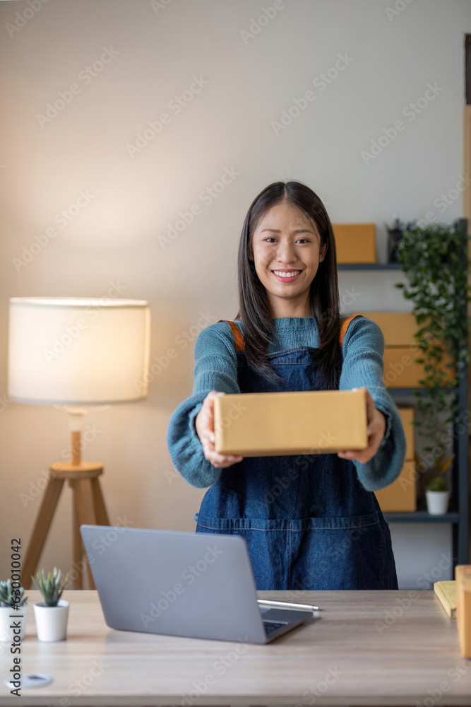 Online business concept, Asian business women holds parcel boxes of product for delivery to client.