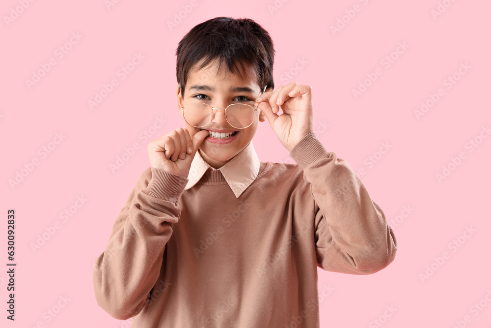 Little boy biting nails on pink background