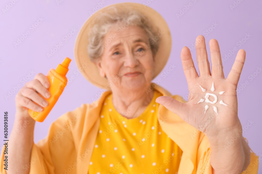 Senior woman with sun made of sunscreen cream on lilac background, closeup