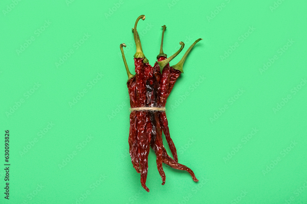 Tied dry hot chili peppers on green background