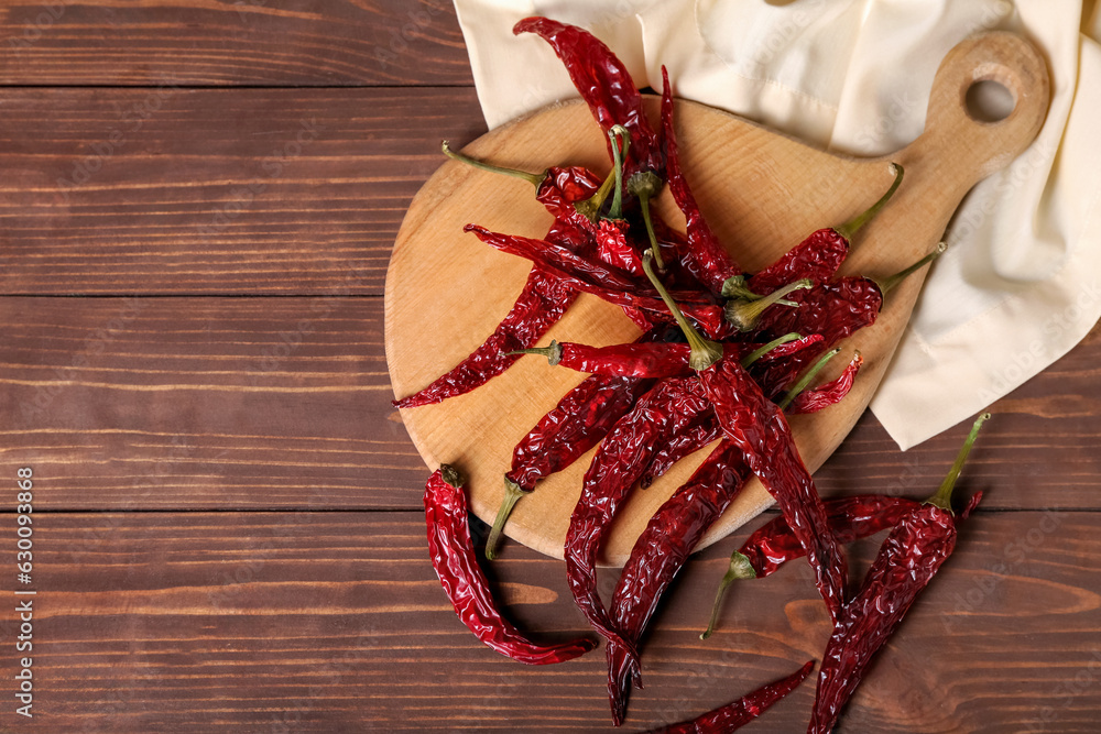 Board with dry hot chili peppers on brown wooden background