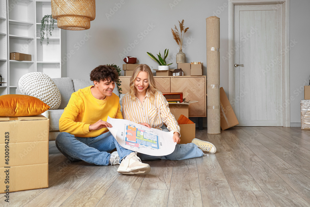 Young couple with house plan sitting in room on moving day