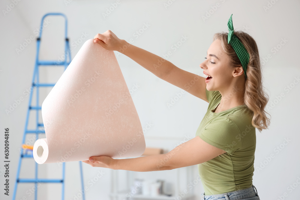 Young woman with wallpaper roll at home