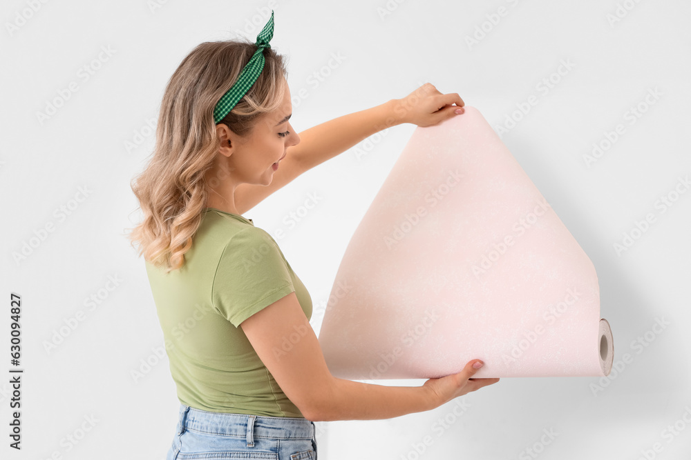 Young woman with wallpaper roll at home