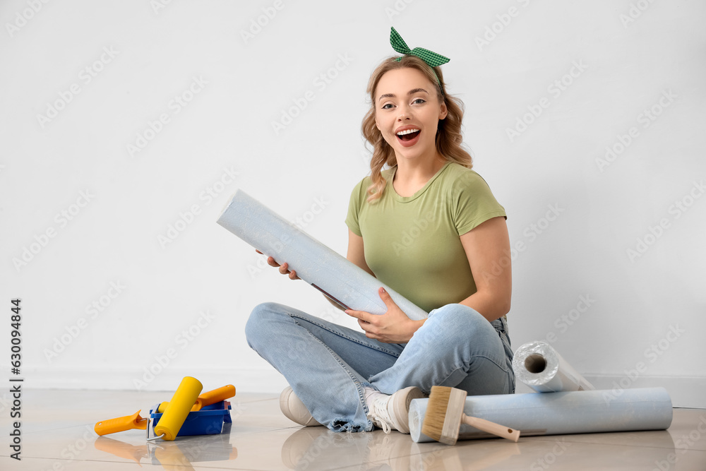 Young woman with wallpaper roll sitting at home