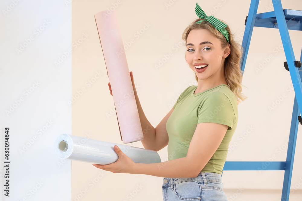 Young woman with wallpaper rolls at home