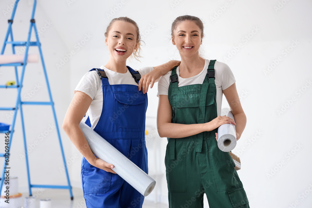 Female decorators with wallpaper rolls in room