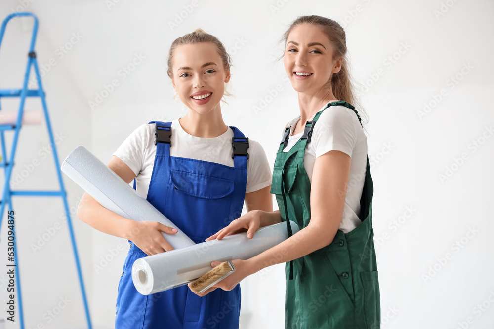 Female decorators with wallpaper rolls in room