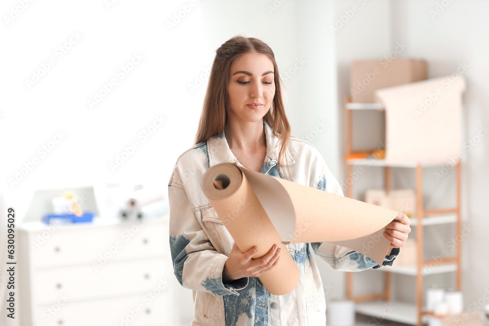 Young woman with wallpaper roll at home