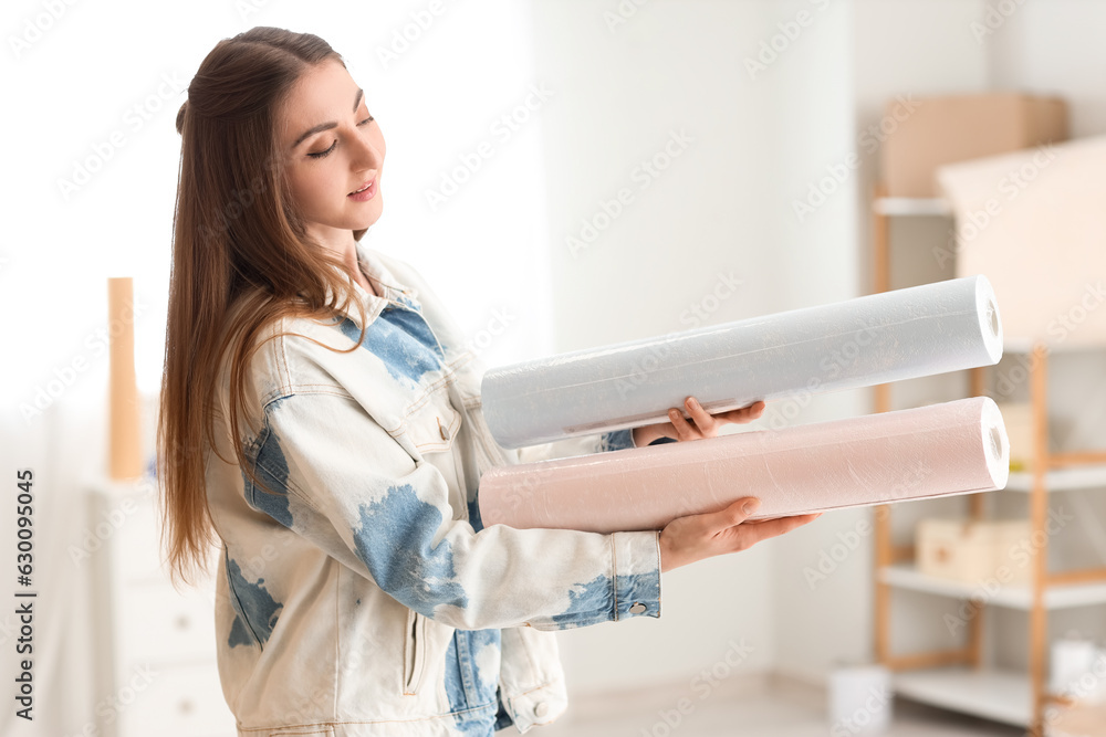 Young woman with wallpaper rolls at home