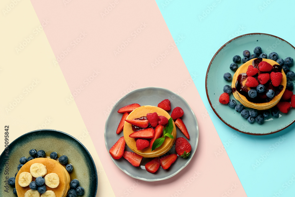 Plates with sweet pancakes and berries on color background