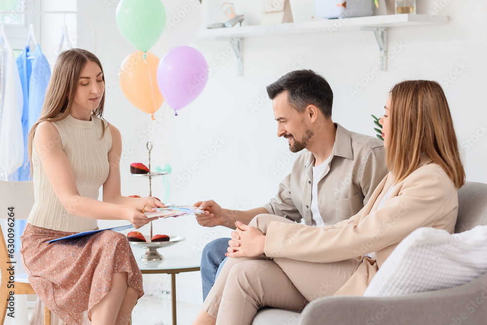 Young couple with wedding planner choosing color palette in office