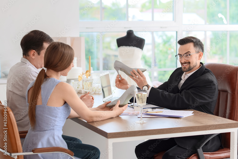 Male wedding planner working with couple in office