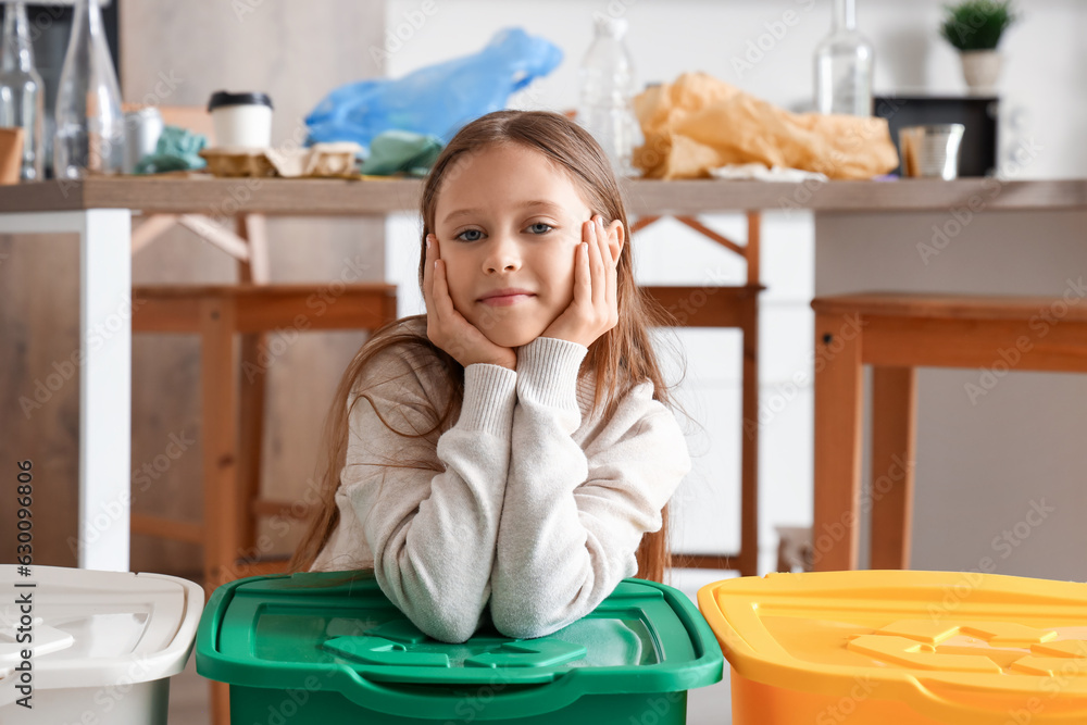 Little girl with recycle trash bins in kitchen