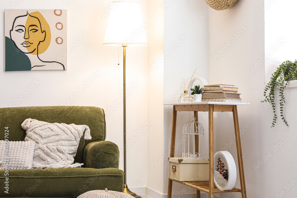 Interior of stylish living room with cozy green sofa, console table and glowing lamp