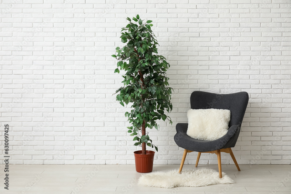 Dark grey armchair with pillow, fluffy rug and houseplant near white brick wall