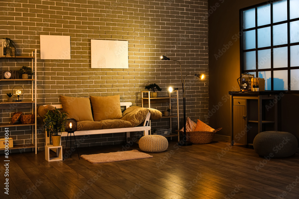 Interior of dark living room with couch, shelving units and glowing lamps