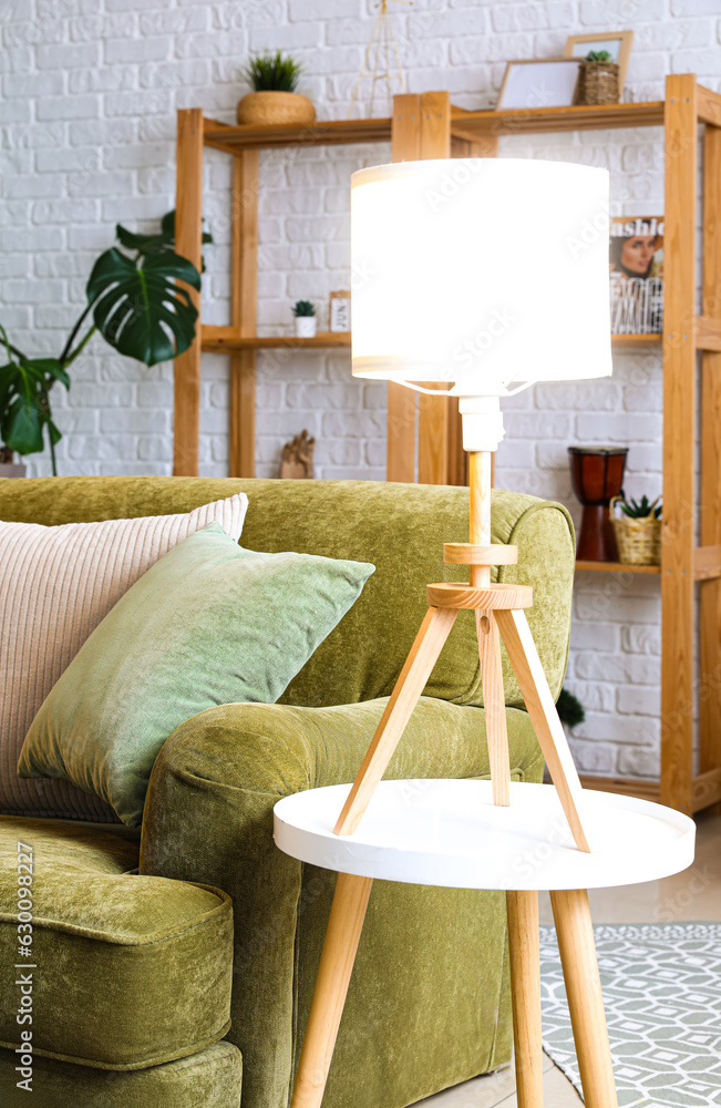 Glowing lamp on table near green sofa in living room