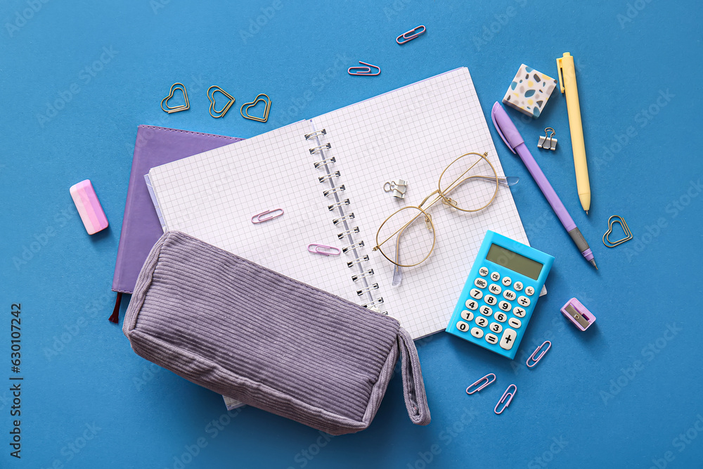 Notebooks with glasses and school stationery on blue background