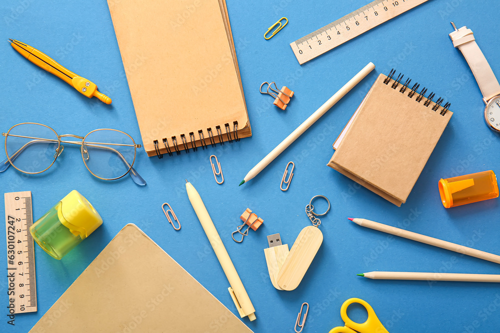 Different school stationery, notebooks and glasses on blue background