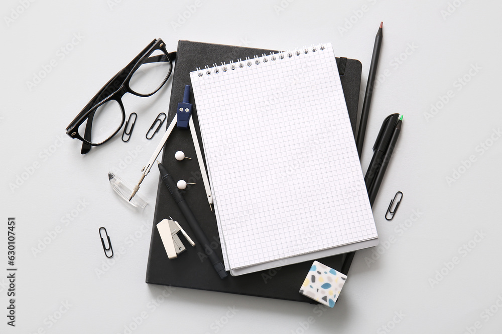 Composition with blank notebook, eyeglasses and different school stationery on white background