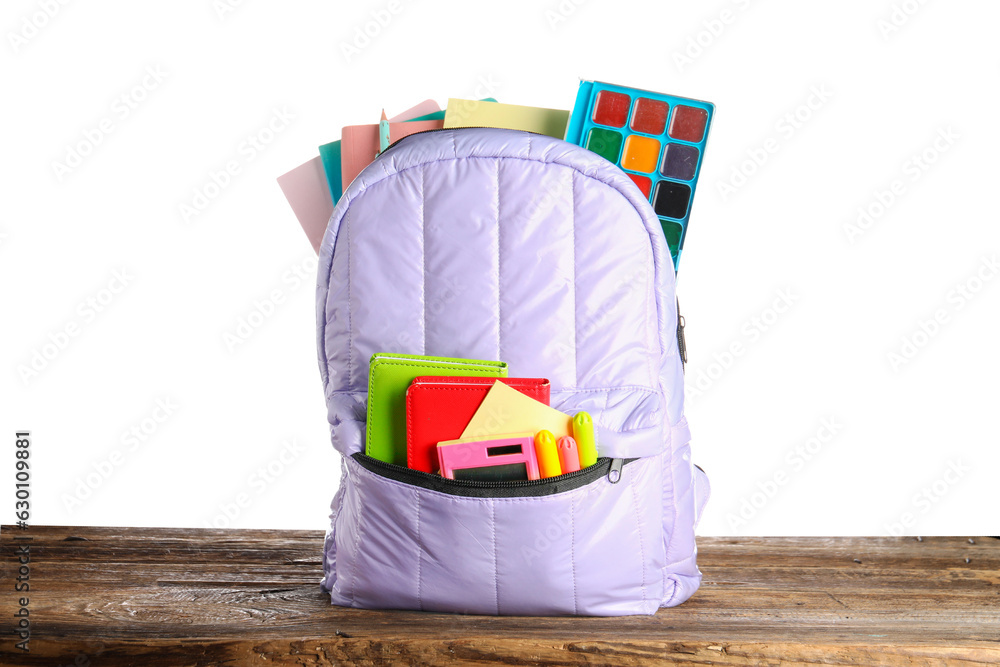 Lilac school backpack with notebooks and watercolors on wooden table near white background