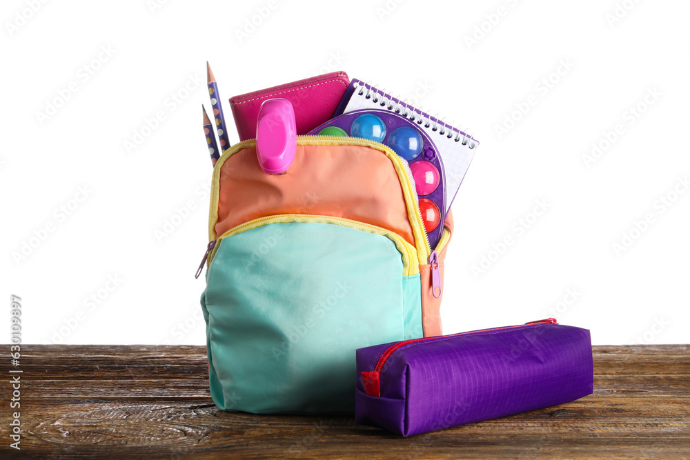 Colorful school backpack with pencil case, notebooks and paints on wooden table near white backgroun