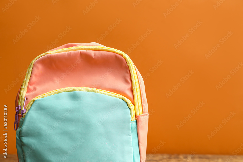 Colorful school backpack on orange background