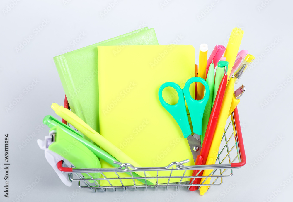 Shopping basket with different stationery on white background