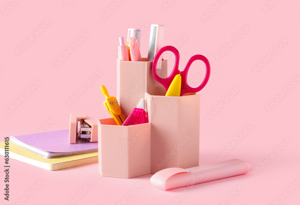 Holder with different stationery on pink background