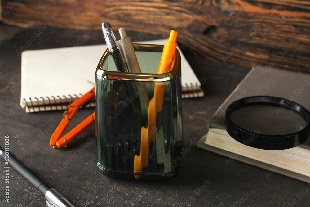 Glass holder with stationery on dark table