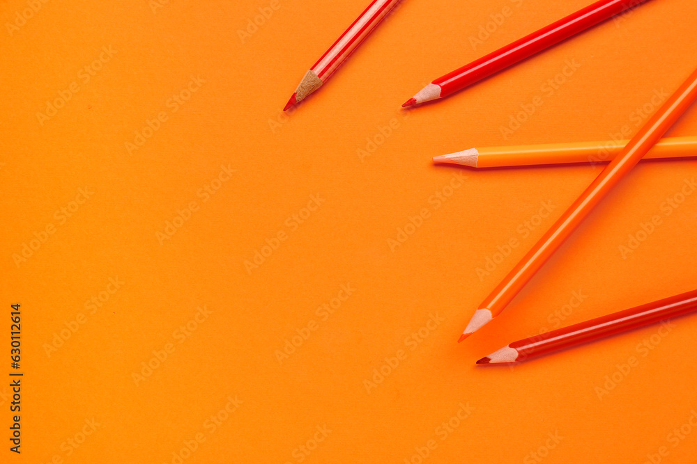 Different pencils on orange background