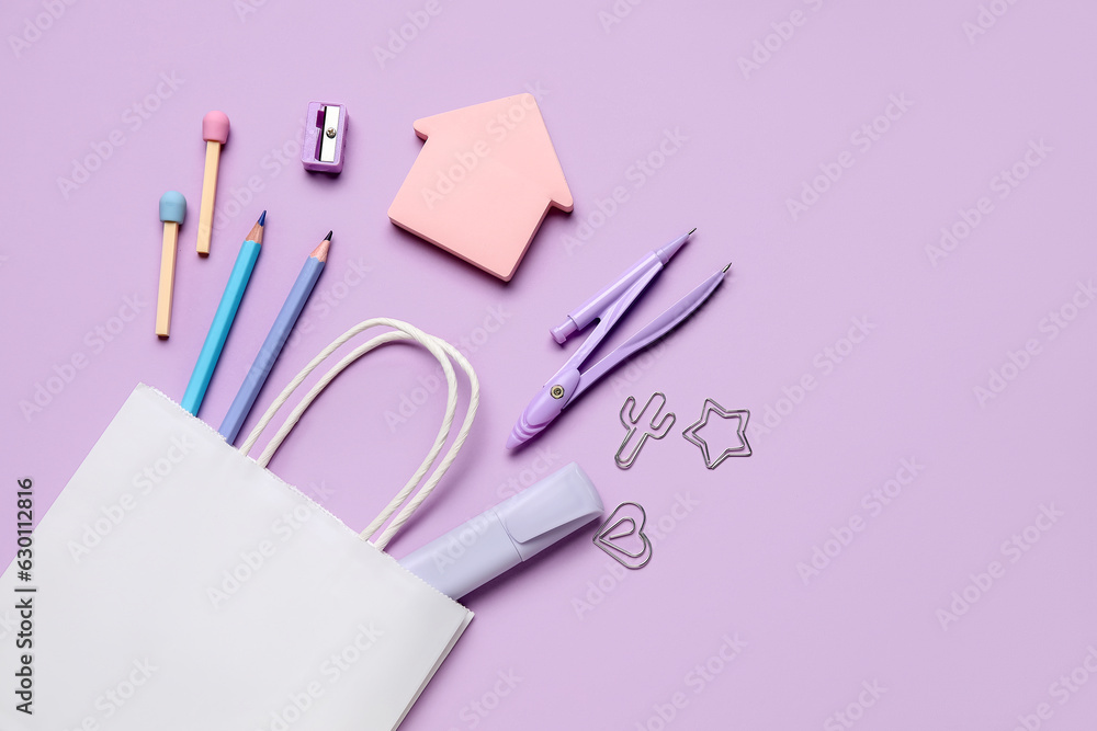 Composition with paper bag and different stationery on lilac background