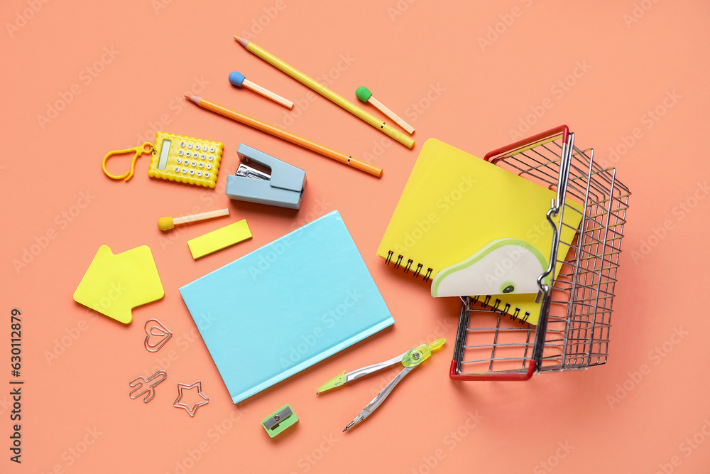 Overturned shopping basket with different stationery on color background