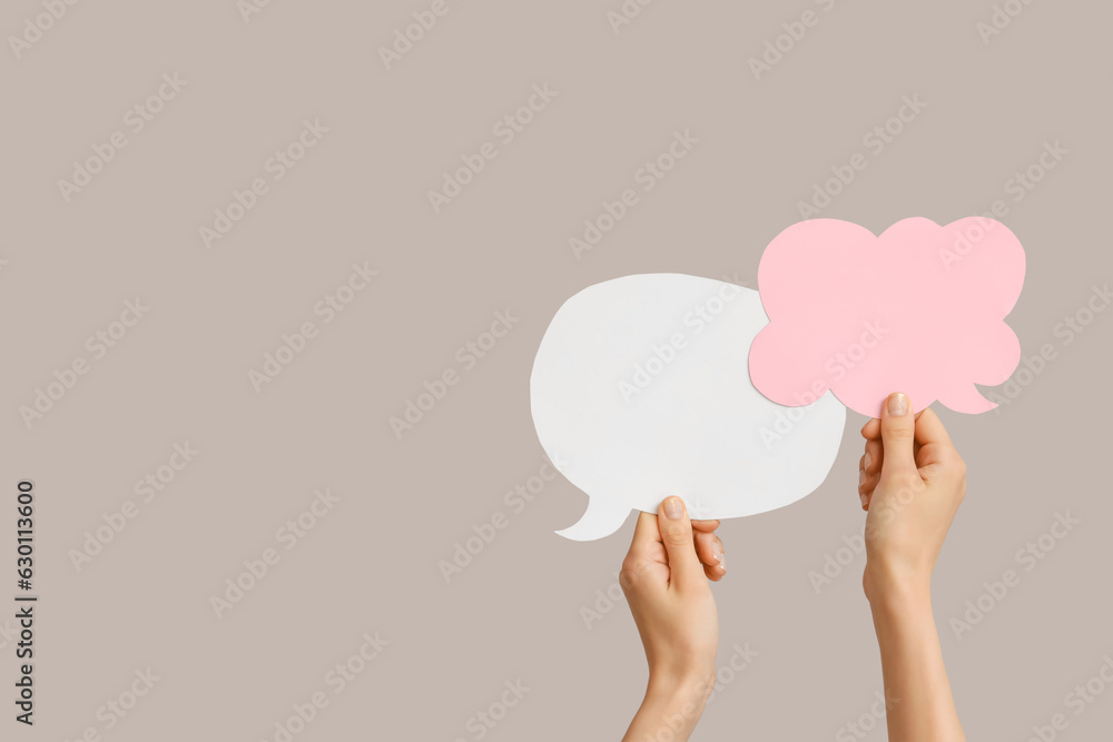 Female hands with speech bubbles on grey background